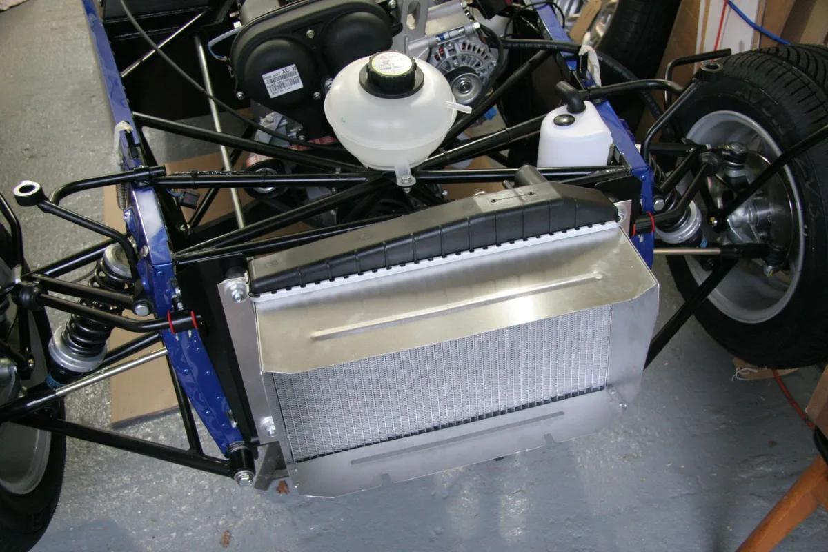 A coolant expansion tank and radiator in an open car engine compartment.