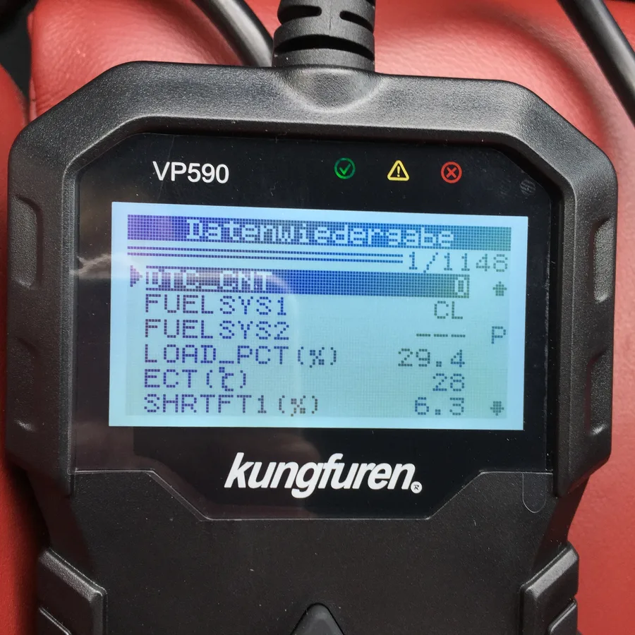 A close photograph of a handheld automotive diagnostic scanner and its illuminated screen.