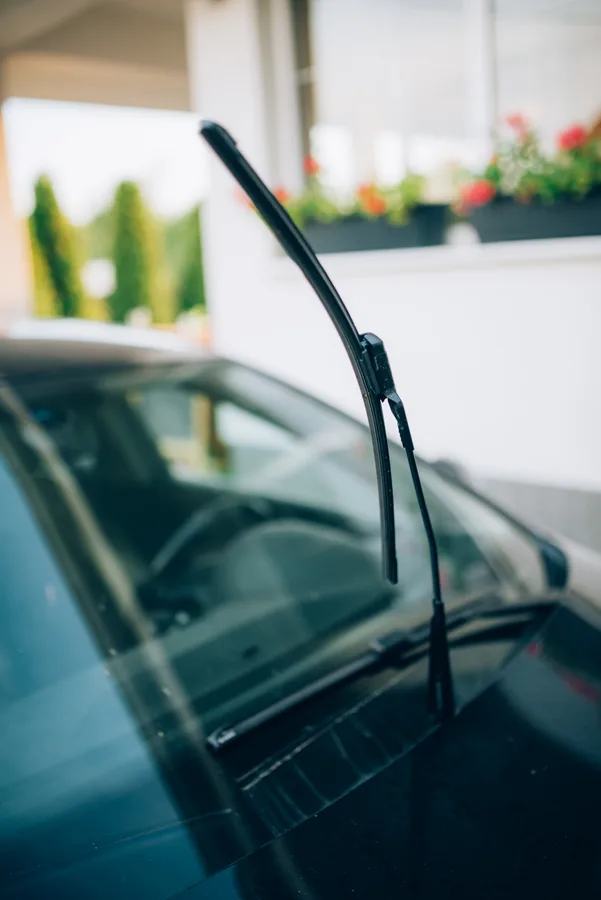 A windshield and raised wiper on a parked car.