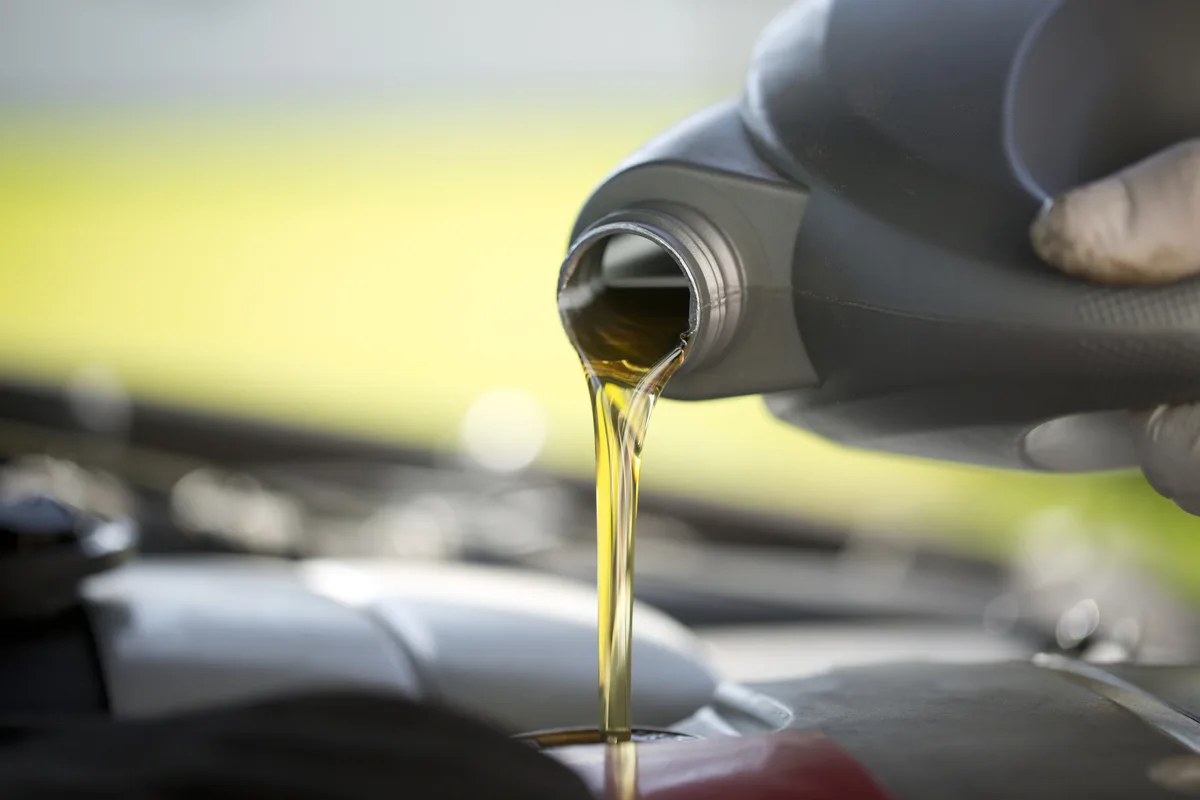 Fresh engine oil pouring into a car engine.